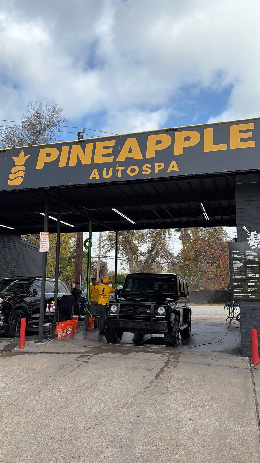 Detailers hand washing an SUV under the Pineapple Autospa canopy in North Houston